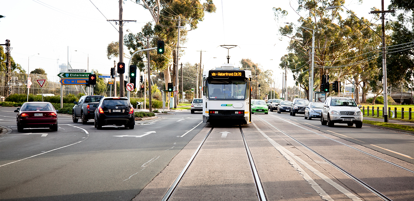 Cars driving next to a tram on a busy road
