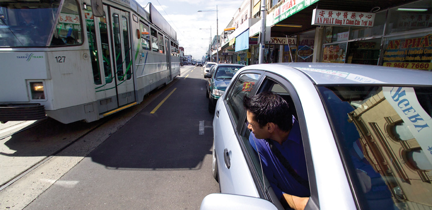 A car next to a tram on a busy road